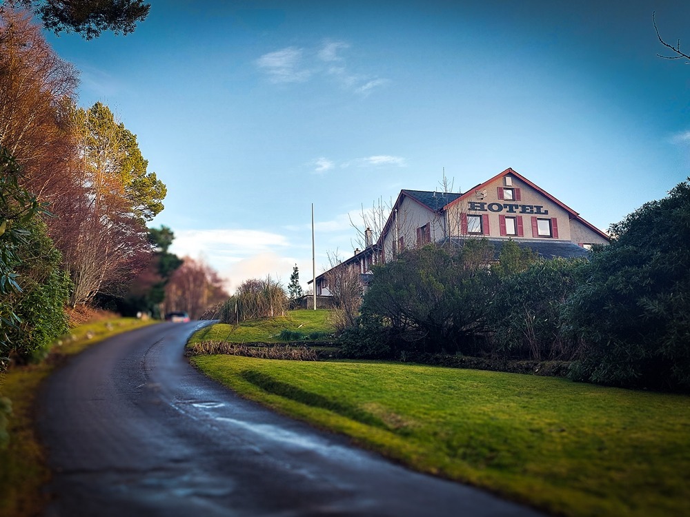 A view of Gairloch Highland Lodge from the approaching road, showing the hotel nestled in the quiet landscape of the North West Highlands.