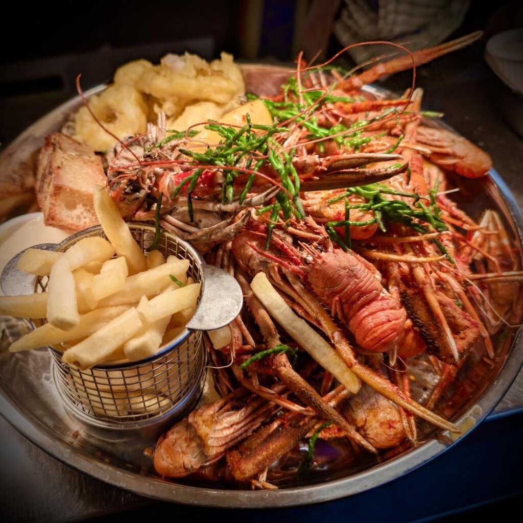 Fresh local seafood platter at our nearby restaurant, The Old Inn, featuring langoustines, calamari, and chips, perfect for diners in Wester Ross.